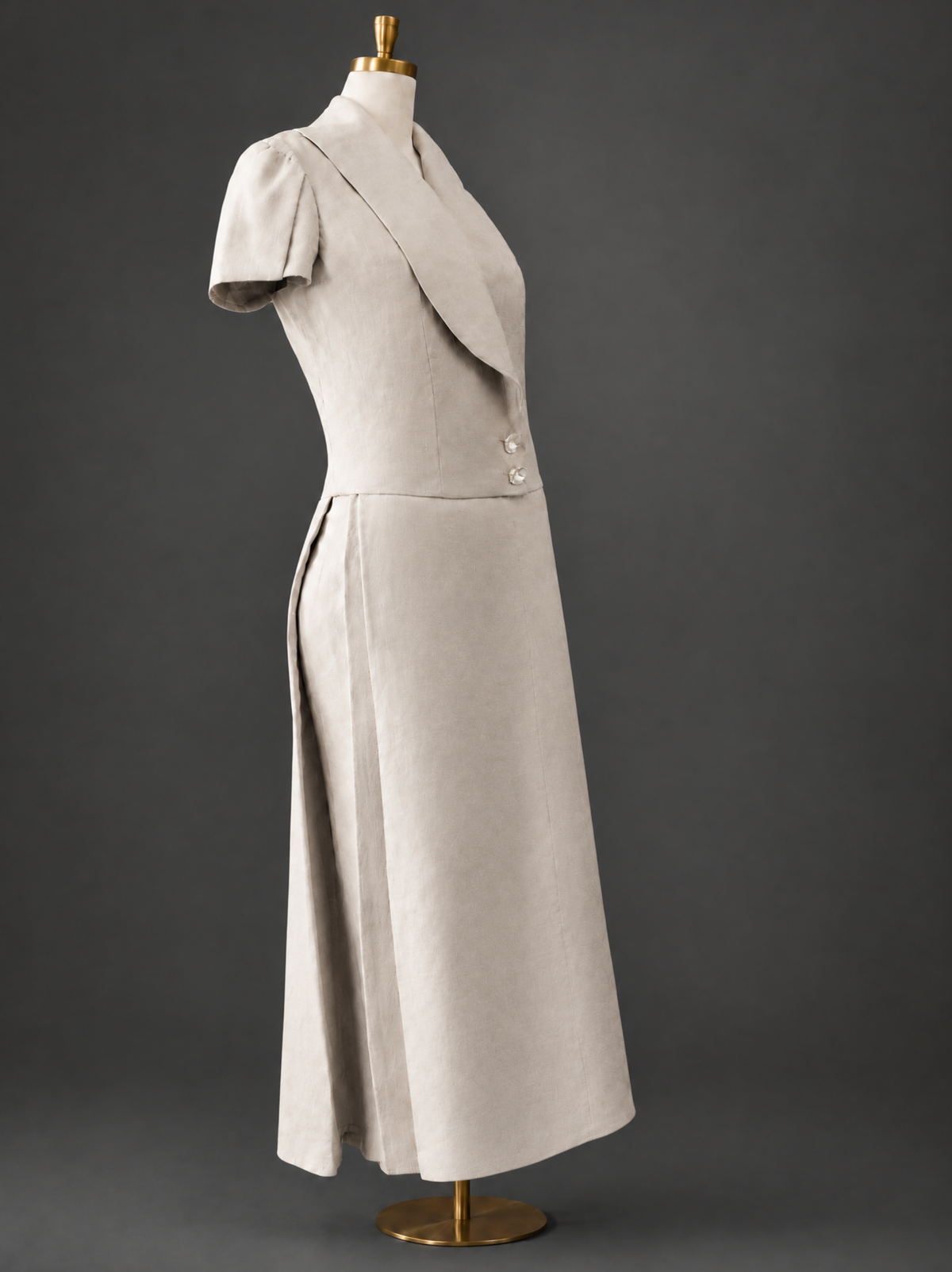 Angled three-quarter view of The Silent Dove linen suit on a dress form, highlighting the high-quality fabric texture and silhouette.
