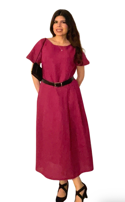 Woman wearing a magenta dress with a black belt on a white background